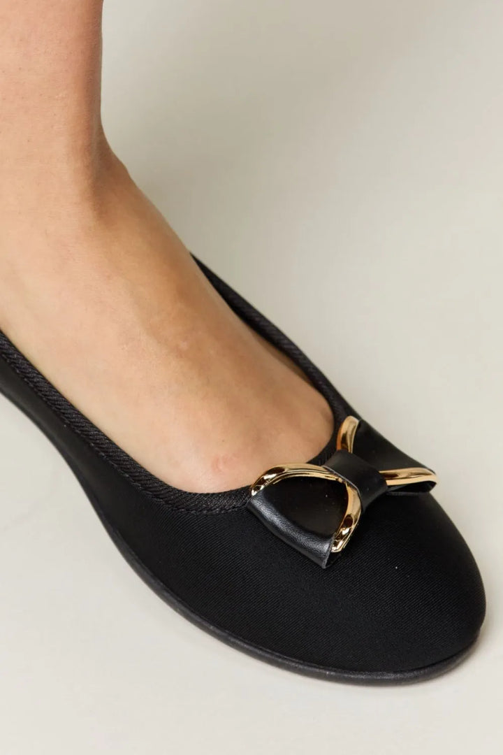 Black flat shoe with a gold buckle
