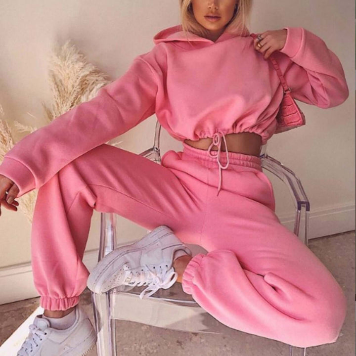 Stylish pink women's jogging suit featuring a cropped hoodie and relaxed-fit pants, perfect for casual fitness wear.